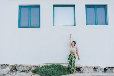 Full length of shirtless young woman standing against wall