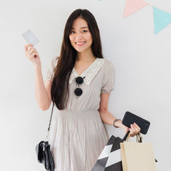 Portrait of a smiling young woman standing against wall