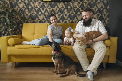 Smiling family with baby girl and pets in living room