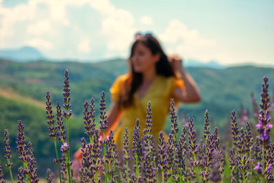 Rear view of woman standing on field against cloudy sky