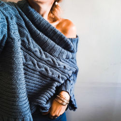 Midsection of woman holding umbrella standing against wall