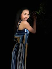 Portrait of smiling woman standing against black background