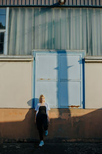 Full length of woman sitting against building