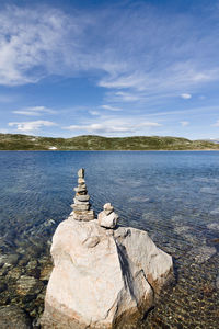 Stack of rocks in lake against sky