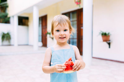 Little cute cheerful girl eating a slice of watermelon close up.