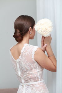 Rear view of young woman sitting on bed at home