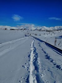 Snow covered landscape against blue sky