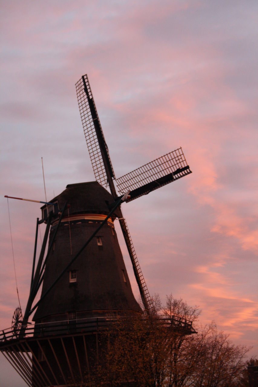 LOW ANGLE VIEW OF TRADITIONAL WINDMILL AGAINST SKY AT SUNSET