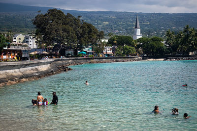 People on sea by buildings in city