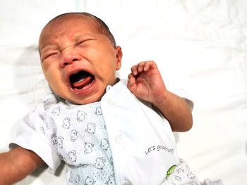 Baby boy crying on bed