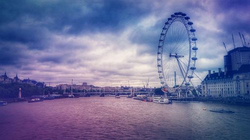 Ferris wheel in city against cloudy sky