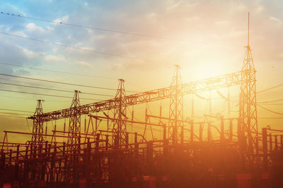 Low angle view of cranes against sky during sunset