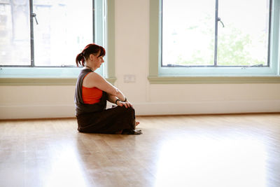 Side view of young woman sitting on floor