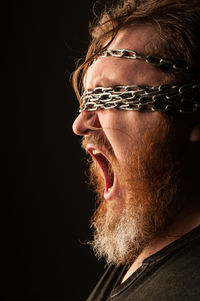 Close-up of mid adult man with chain against black background