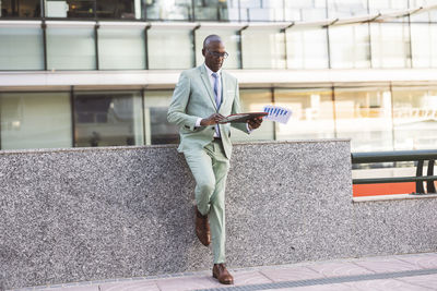 Mature businessman with documents leaning on wall