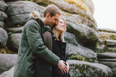 Smiling heterosexual couple standing against rock