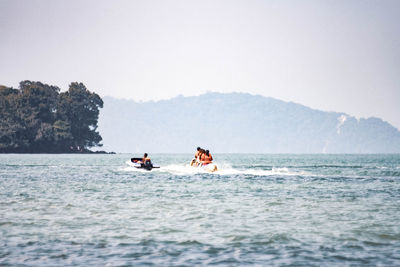 People on boat in sea against clear sky