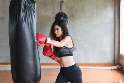 Young woman hitting punching bag in studio