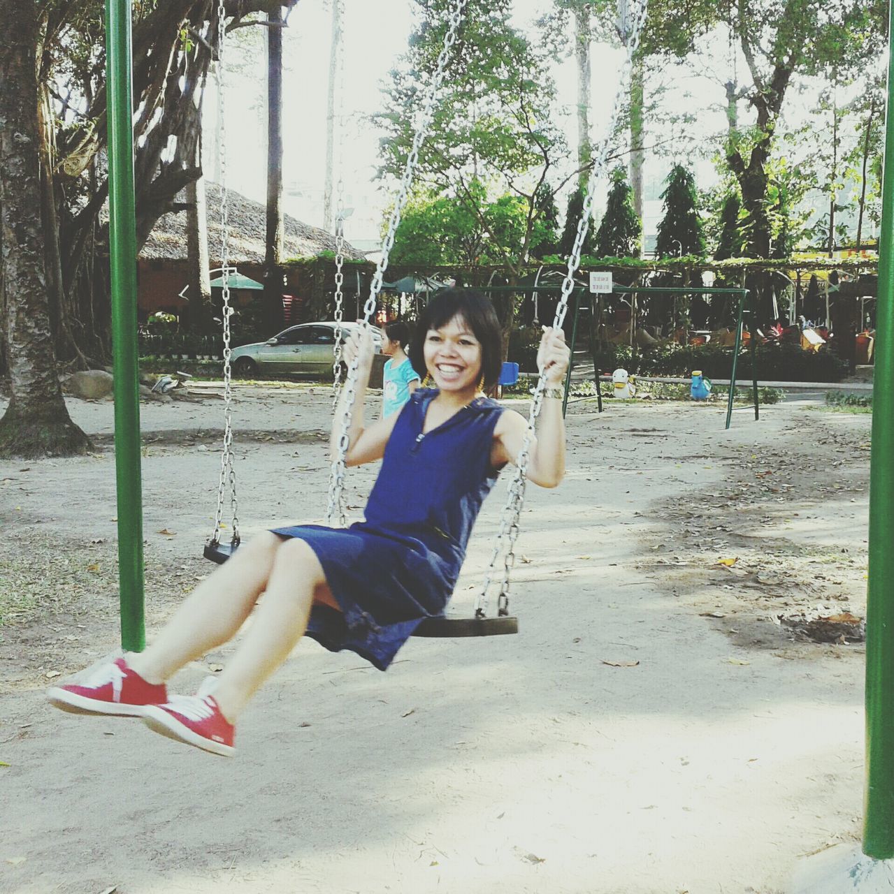 person, lifestyles, leisure activity, casual clothing, young adult, looking at camera, portrait, sitting, young women, smiling, full length, happiness, front view, tree, sunlight, enjoyment, park - man made space, relaxation