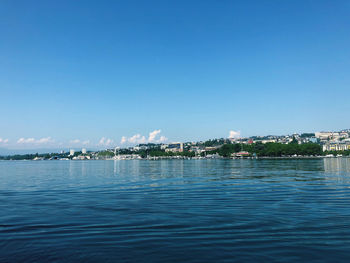 Scenic view of sea by buildings against blue sky