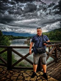 Full length of man standing on railing against sky