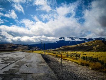 Road leading towards mountains against sky