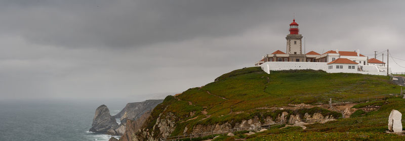 Lighthouse by sea against sky