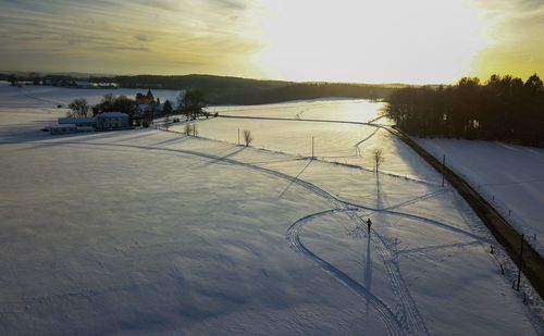 Scenic view of snow covered field against sky during sunset