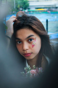 Portrait of beautiful young woman with flower on face