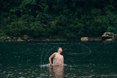 Full length of shirtless man in lake against trees