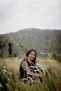 Portrait of smiling young woman sitting on grassy field