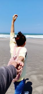 Rear view of people at beach against sky