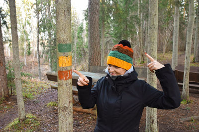 Rear view of man standing by trees in forest