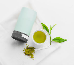 Close-up of herbal tea with leaves over white background