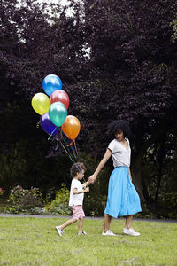 Mother with son walking with bunch of balloons