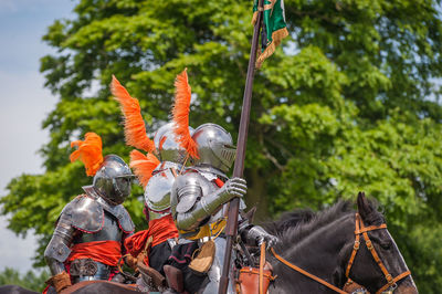 Men riding horses on field against sky