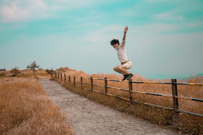 Full length of man jumping on dirt road