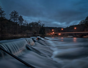 Scenic view of waterfall against sky at dusk