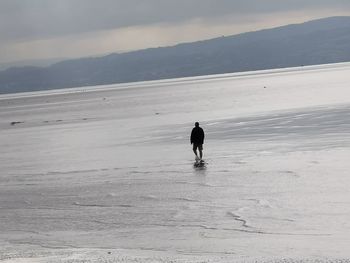 Full length of woman standing on beach against sky