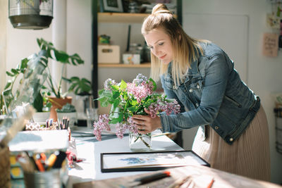 Woman holding flower pot on table