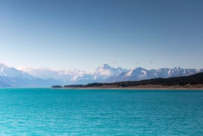 Scenic view of sea and mountains against clear blue sky