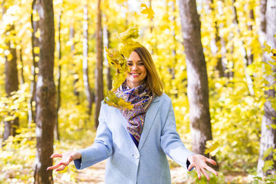 Happy young woman standing in forest during autumn