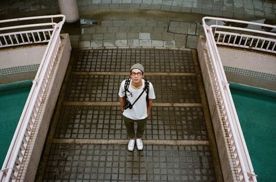 High angle portrait of young woman standing on historic building