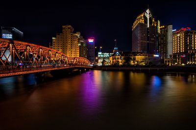 Illuminated bridge over river at night