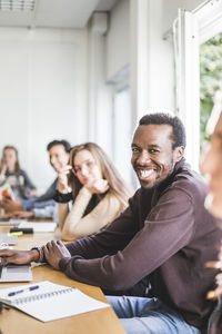 Portrait of smiling young man sitting in classroom