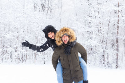 Portrait of smiling young woman standing in snow