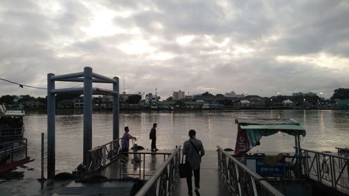 People on bridge against sky in city