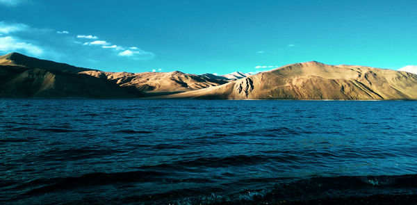 Scenic view of lake and mountains against blue sky