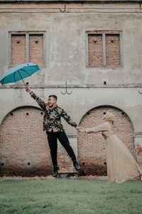 Man holding umbrella standing against building