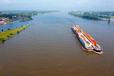Aerial from a freighter full of containers cruising on the river merwede in the netherlands 